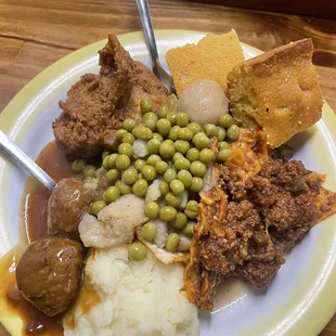 a plate of meat, mashed potatoes and peas