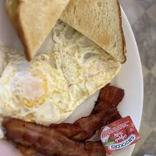Two egg breakfast with eggs over medium toast and bacon.
