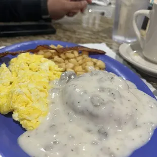 a blue plate with eggs, sausage, and waffles