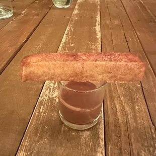 a wooden table with a glass of water and a piece of bacon on it