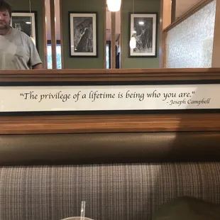 a man standing in front of a sign that says the privilege of a lifetime is being what you are