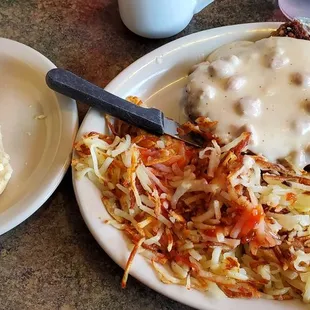 Chicken fried steak with sausage gravy, hash browns, and biscuit