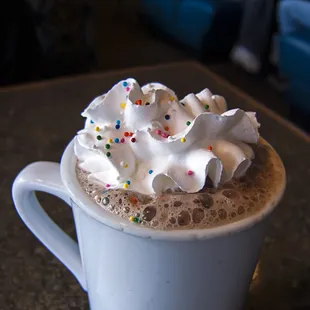 a cup of hot chocolate with whipped cream and sprinkles