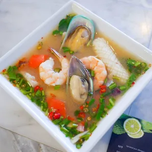 a bowl of soup with seafood and vegetables