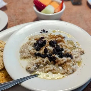 Creamy oatmeal loaded with butter, brown sugar, raisins and milk, plus fresh fruit and sourdough toast.
