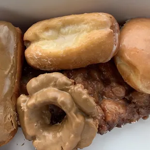 Left to right: maple bar, buttermilk, old fashion maple, two Apple fritters underneath, jelly filled donut