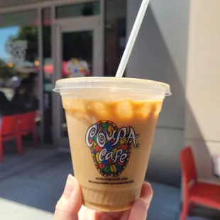 a hand holding a cup of iced coffee