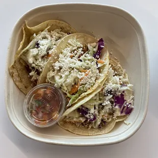 a plate of tacos with cole slaw and a drink