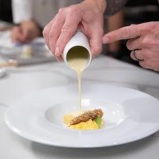 a chef pouring sauce onto a dish