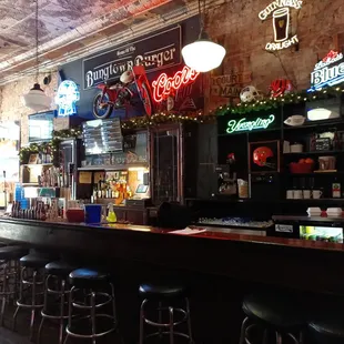 a bar with stools and neon signs