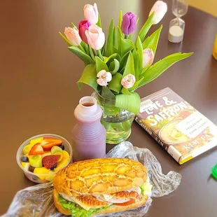 a sandwich, fruit, and a book on a table