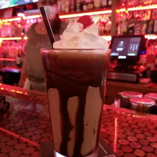 a chocolate milkshake with whipped cream and a cherry on top