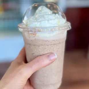 a hand holding a cup of milkshake
