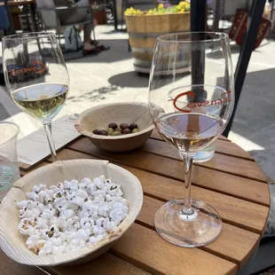 a bowl of popcorn and two glasses of wine