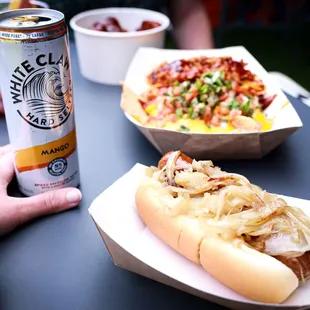 a person holding a beer and a hot dog