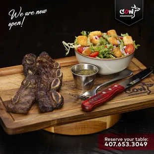 a bowl of salad and steak on a cutting board