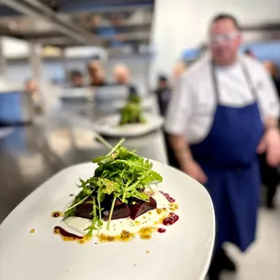 a chef in a kitchen with a plate of food