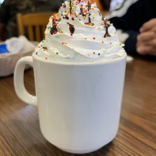 a cup of coffee with whipped cream and sprinkles