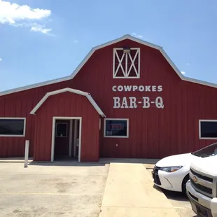 ows a white truck parked in front of a red barn