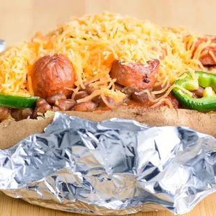 a hot dog wrapped in foil with cheese and jalapenos