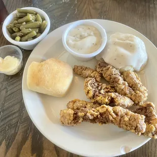 Beef fingers with country gravy, mashed potatoes, green beans and a roll.