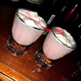 two shot glasses with whipped cream and strawberries