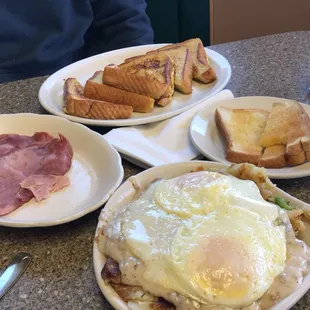 a plate of eggs, toast, ham and toast