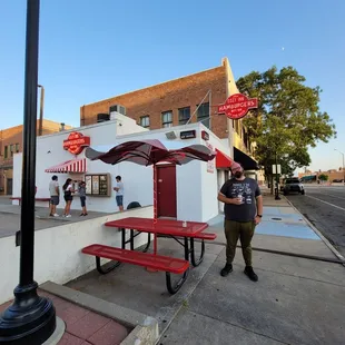 a man standing in front of a red picnic table