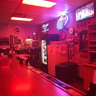 a bar with neon signs and a refrigerator