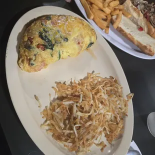 Philly cheesesteak and fries and a Veggie omelet with bacon in it and hashbrowns