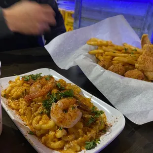 a plate of shrimp and macaroni and cheese fries