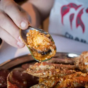 a person holding a spoon full of crab nuzzles