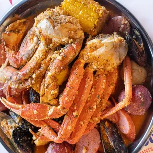 a bowl of crab legs, corn, potatoes, and sausage