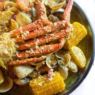 a plate of crab legs, corn, and potatoes