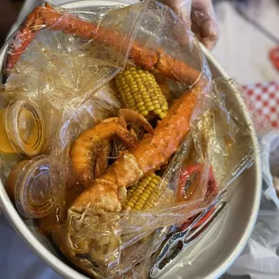 a person holding a bowl of crab and corn