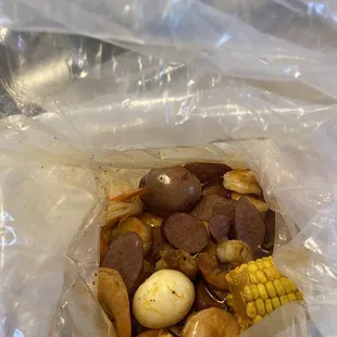 a bag of food with sausage, corn and potatoes