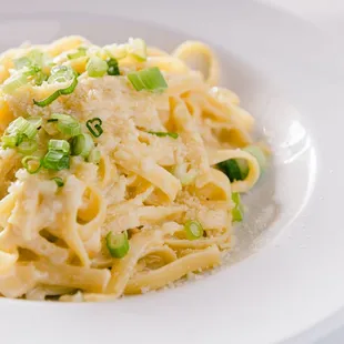 a plate of pasta with green onions and parmesan cheese