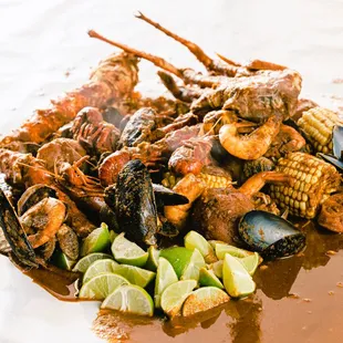 a plate of seafood and corn with lime wedges