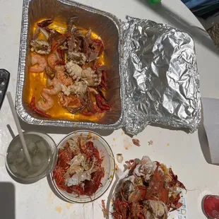 a tray of cooked lobsters and other food