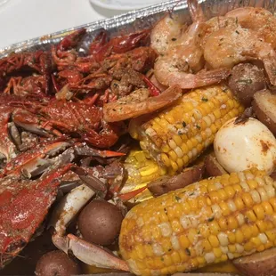 crab, corn, potatoes, and corn on a foil pan