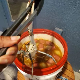  a person using a tong to stir a pot of soup