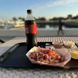 a bottle of soda and a tray of food