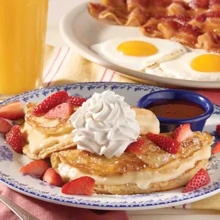 a plate of pancakes with whipped cream and strawberries