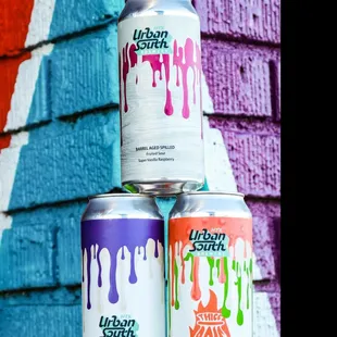 three cans of craft beer in front of a graffiti wall