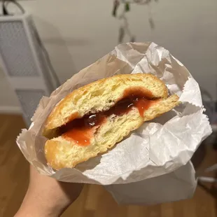 a hand holding a sandwich with jam on it