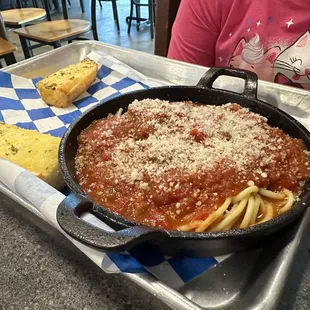 a skillet of spaghetti and bread
