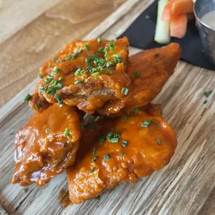 chicken wings on a cutting board with carrots and celery