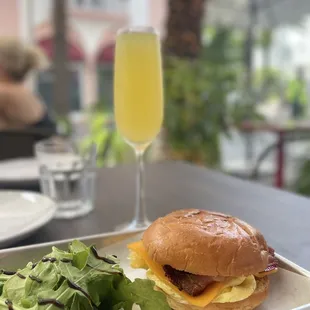 Breakfast Sandwich Bacon, Scrambled Eggs, Cheddar Cheese, Tomato Relish, Green Salad and Mimosa Glass