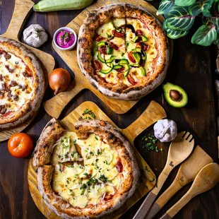 three pizzas on wooden cutting boards