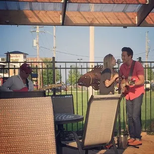 a man and woman playing guitar on a patio